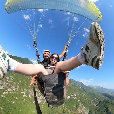 Passenger laughing with legs stretched out over the valley, mid-flight.